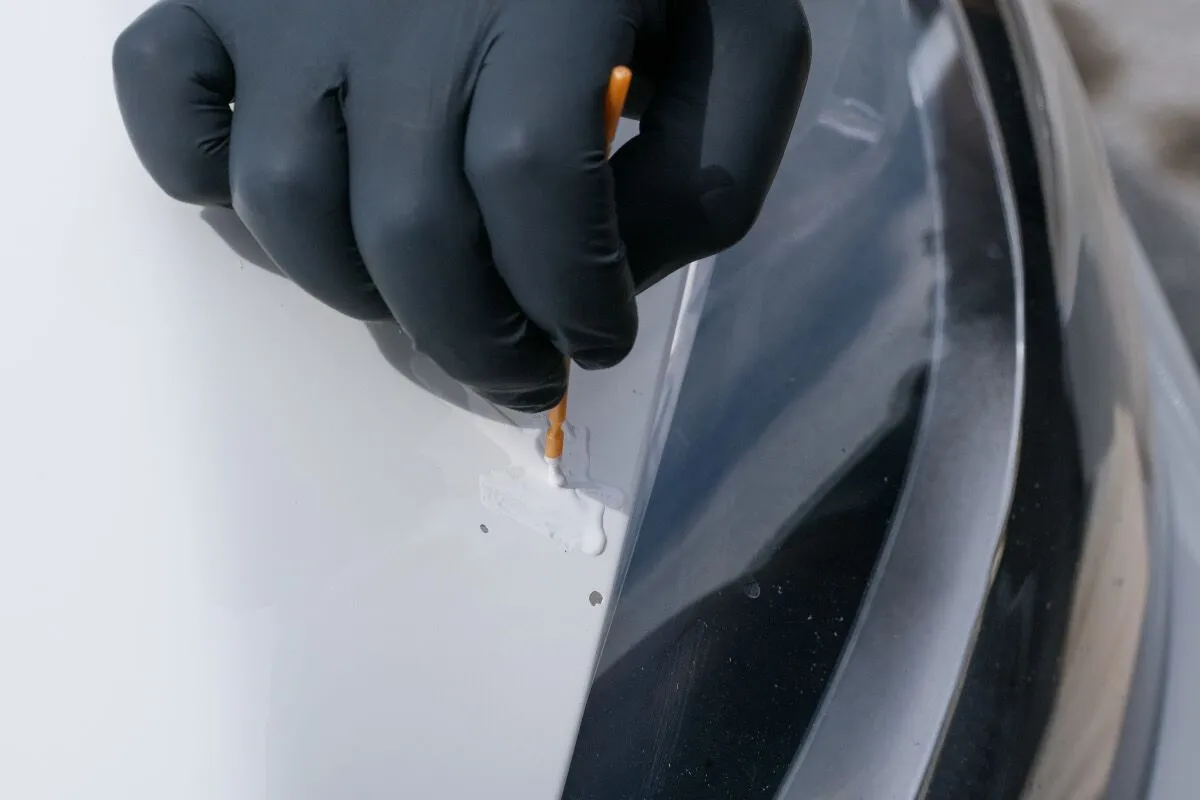 Applying factory-matched Dr. ColorChip touch-up paint beside a paint chip