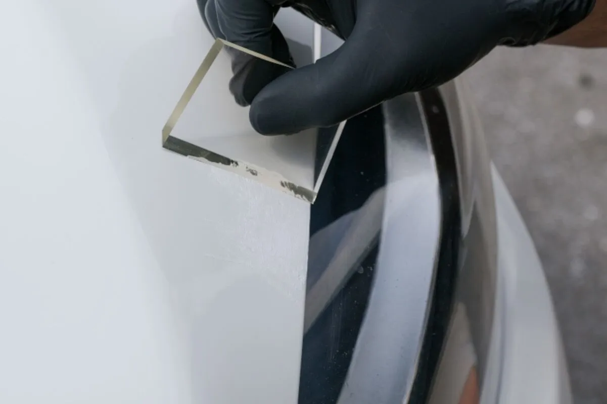 Leveling Dr. ColorChip touch-up paint across automotive paint chips with a flexible squeegee