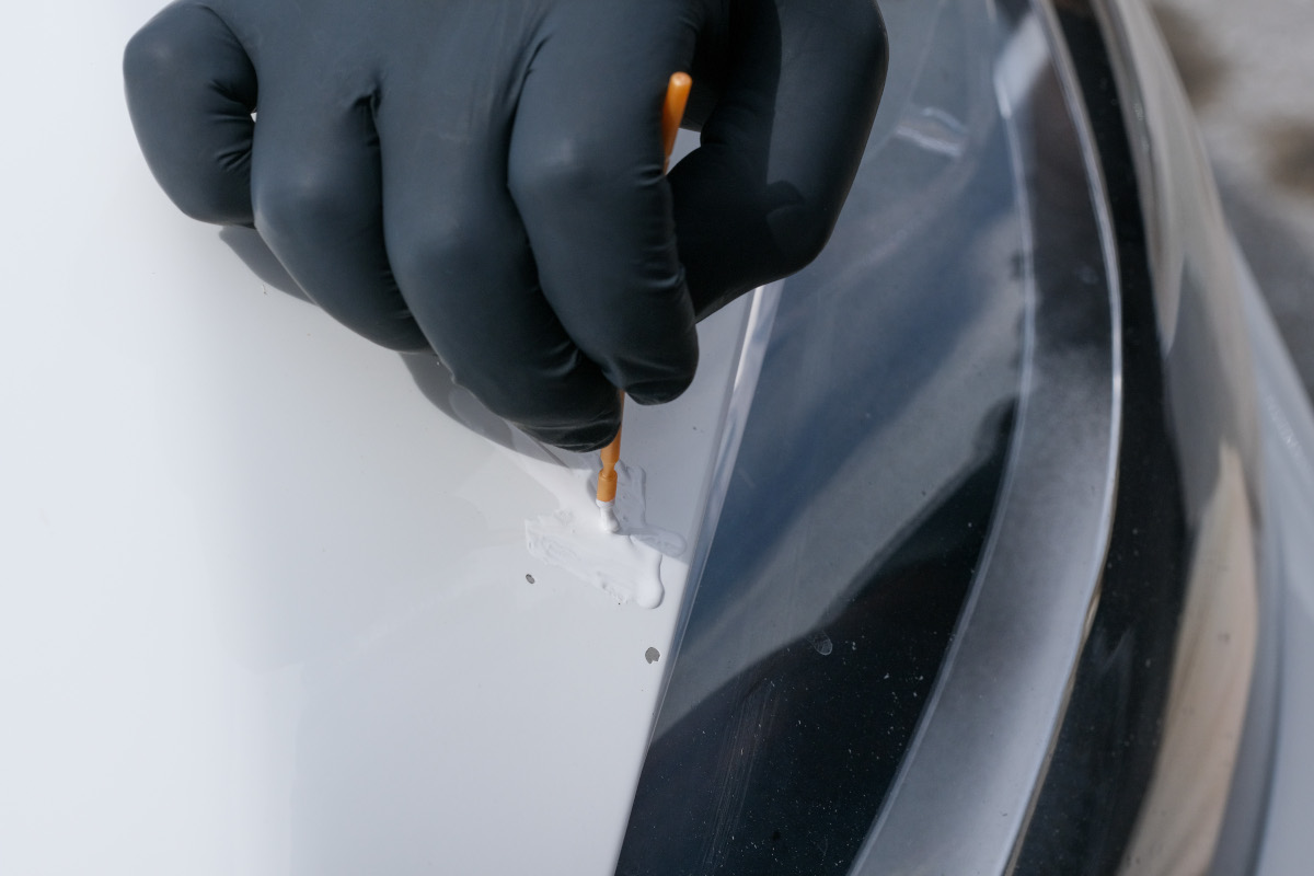 Applying factory-matched Dr. ColorChip touch-up paint beside a paint chip